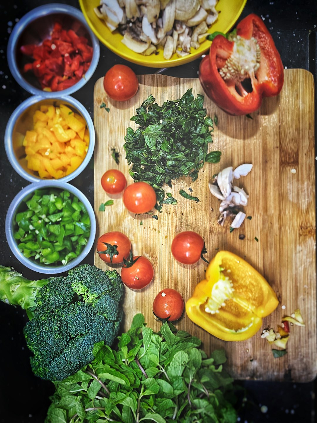 Verduras y hierbas coloridas preparadas sobre un mostrador oscuro.