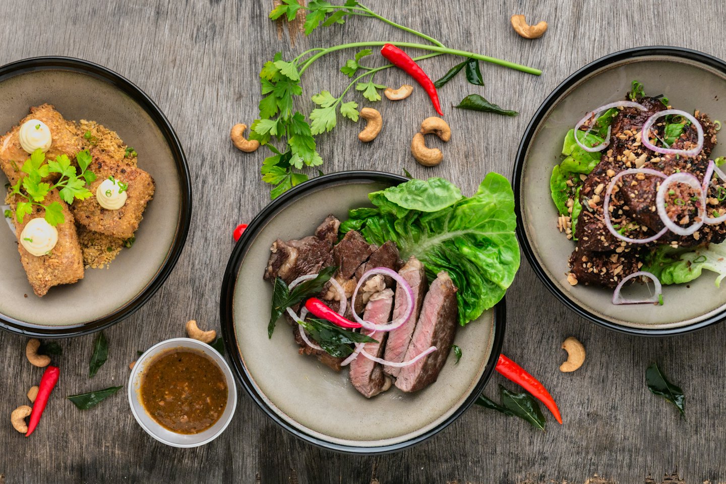 Tres deliciosas comidas dispuestas artísticamente sobre una mesa de madera.